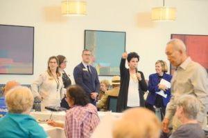 Staff members standing and speaking with residents during a group community event.