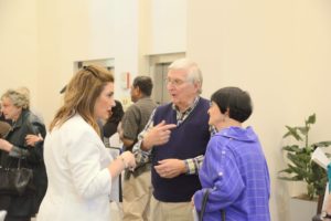 Residents and staff standing and talking together during a social event.