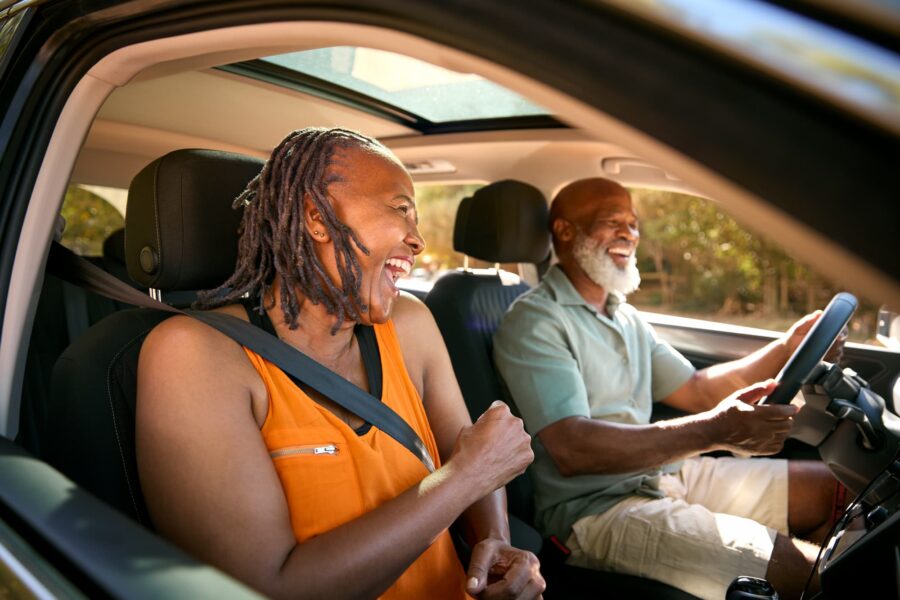 A happy senior couple laughing and smiling as they sit in the front seats of a SUV