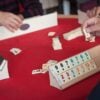 several seniors gather around a table playing a dominos game together.
