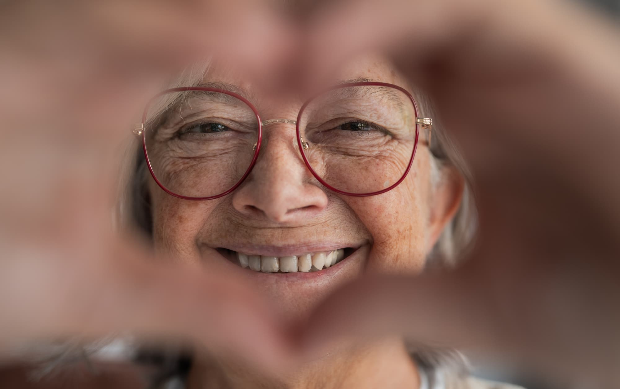 senior woman making a heart symbol with her hands and smiling