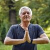 man conducting some yoga poses while meditating in an outdoor park