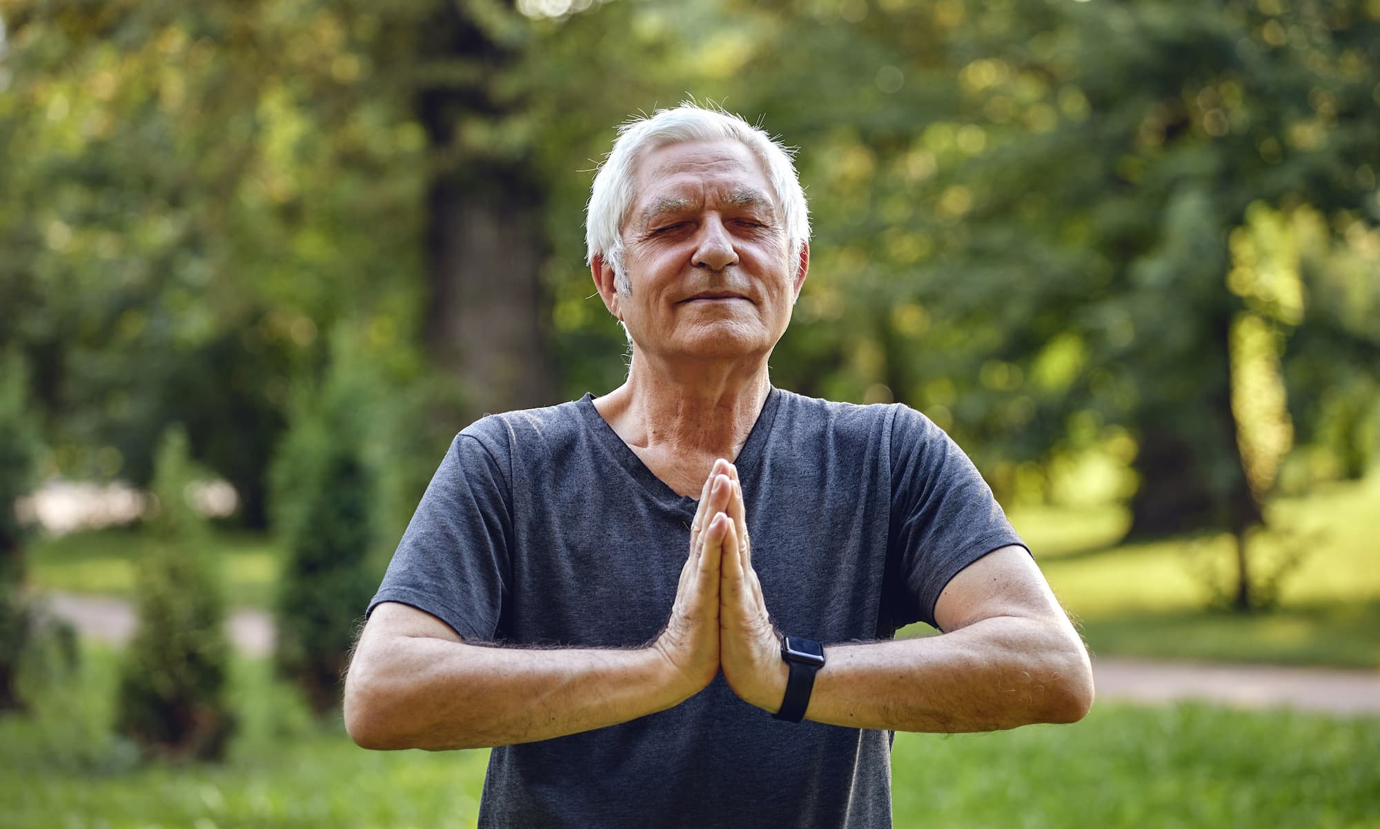 man conducting some yoga poses while meditating in an outdoor park